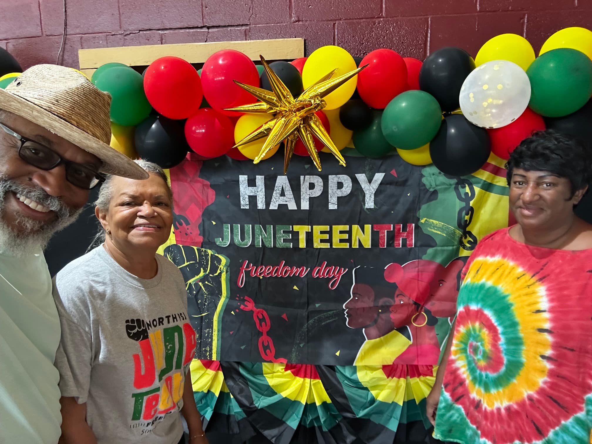 Two community members posing at the Happy Juneteenth photo booth with balloons