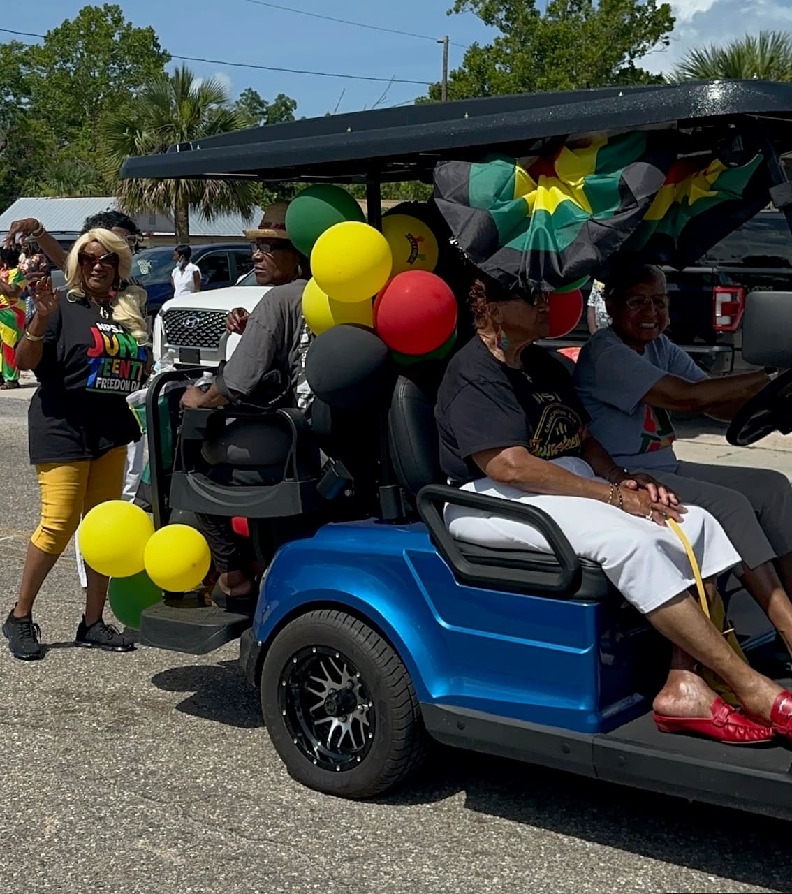 Golf cart decorated with Juneteenth balloons and Freedom Day banner in the parade