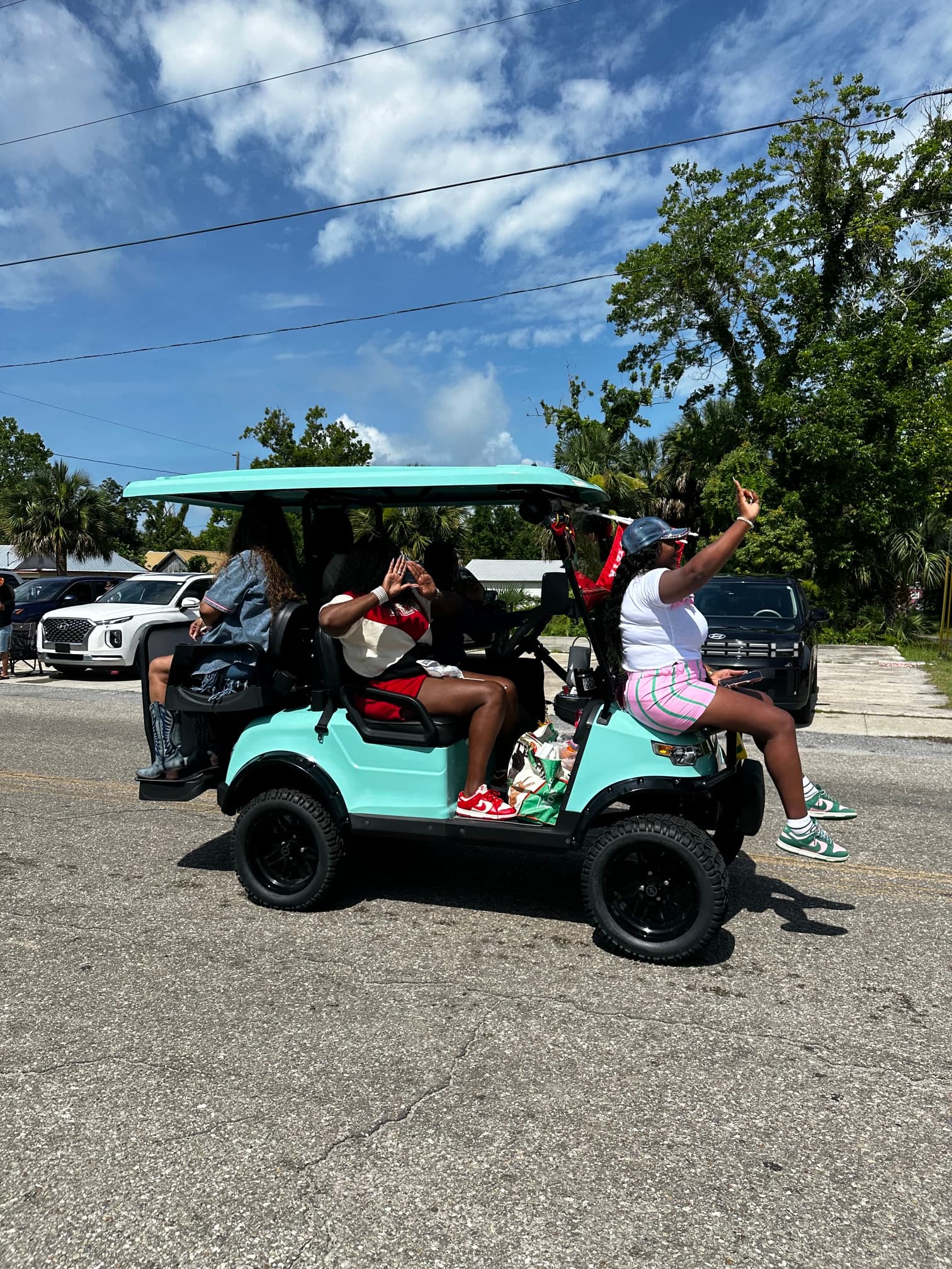 Community members riding a teal golf cart in the Juneteenth parade